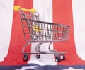 Mini empty supermarket shopping cart over American flag. Consuption concept