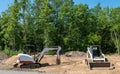 A mini excavator and compact front loader on dirt at home construction lot Royalty Free Stock Photo