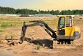 Mini excavator at construction site. Backhoe on earthwork. Digg trench to lay cables concrete curbs and paving slabs. Loader on Royalty Free Stock Photo