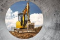 Mini excavator at the construction site on the edge of a pit against a cloudy blue sky. Compact construction equipment for Royalty Free Stock Photo