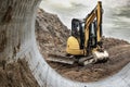 Mini excavator at the construction site on the edge of a pit against a cloudy blue sky. Compact construction equipment for Royalty Free Stock Photo