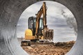 Mini excavator at the construction site on the edge of a pit against a cloudy blue sky. Compact construction equipment for Royalty Free Stock Photo