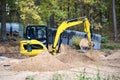 Mini excavator at construction site surrounded by trees. Compact construction equipment for operative earthworks. Tracked yellow Royalty Free Stock Photo
