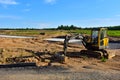 Mini excavator digg trench to lay cables concrete curbs and paving slabs at construction site. Backhoe on earthwork/roadworks