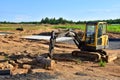 Mini excavator digg trench to lay cables concrete curbs and paving slabs at construction site. Backhoe on earthwork/roadworks