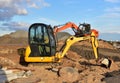 Mini excavator during earthmoving at construction site. Backhoe dig ground for the construction of foundation and laying sewer Royalty Free Stock Photo