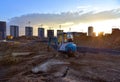 Mini excavator during earthmoving at construction site on sunset background. ÃÂ¡onstruction machinery. Backhoe on roadwork Royalty Free Stock Photo