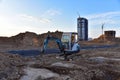 Mini excavator during earthmoving at construction site on sunset background. ÃÂ¡onstruction machinery. Backhoe on roadworks lay Royalty Free Stock Photo