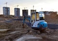 Mini excavator during earthmoving at construction site on sunset background. ÃÂ¡onstruction machinery. Backhoe on roadworks lay Royalty Free Stock Photo
