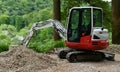 Mini excavator on the mountain surrounded by trees
