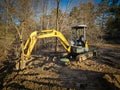 mini excavator positioned on a dirt surface a construction site by a green manhole cover Royalty Free Stock Photo