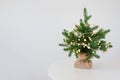 Mini festive christmas tree with lights on white Table wall background Royalty Free Stock Photo