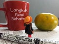 Mini figure standing in front of red mug and fruit Royalty Free Stock Photo