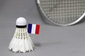 Mini France flag stick on the white shuttlecock on the grey background and out focus badminton racket