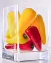 Mini fresh multicolored peppers, stacked in a rectangular glass vase