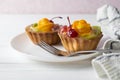 Mini fruit tarts with orange cherry and kiwi on white plate Royalty Free Stock Photo