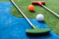 Mini-golf clubs and balls of different colors laid on artificial grass. Royalty Free Stock Photo