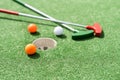 Mini-golf clubs and balls of different colors laid on artificial grass. Royalty Free Stock Photo