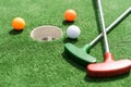 Mini-golf clubs and balls of different colors laid on artificial grass. Royalty Free Stock Photo