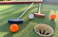 Mini-golf clubs and balls of different colors laid on artificial grass. Royalty Free Stock Photo