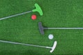 Mini-golf clubs and balls of different colors laid on artificial grass Royalty Free Stock Photo