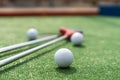 Mini-golf clubs and balls of different colors laid on artificial grass Royalty Free Stock Photo