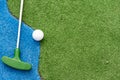 Mini-golf clubs and balls of different colors laid on artificial grass. Royalty Free Stock Photo