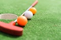 Mini-golf clubs and balls of different colors laid on artificial grass. Royalty Free Stock Photo