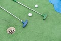 Mini-golf clubs and balls of different colors laid on artificial grass