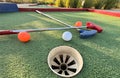 Mini-golf clubs and balls of different colors laid on artificial grass. Royalty Free Stock Photo