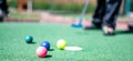 Mini golf game with several colored balls in the way of a putter lined up. Royalty Free Stock Photo