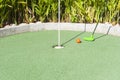 Green Mini Golf Club Putting an Orange Ball