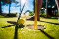 Mini Golf yellow ball with a bat near the hole at sunset Royalty Free Stock Photo