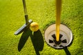 Mini Golf yellow ball with a bat near the hole at sunset Royalty Free Stock Photo