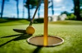 Mini Golf yellow ball with a bat near the hole at sunset Royalty Free Stock Photo