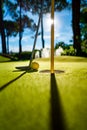 Mini Golf yellow ball with a bat near the hole at sunset Royalty Free Stock Photo