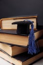 Mini graduation hat on stack of books. Vertical image