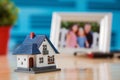 mini house with a family photo frame in the background on a desk Royalty Free Stock Photo