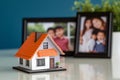 mini house with a family photo frame in the background on a desk Royalty Free Stock Photo