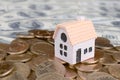 Mini house model on big coins stack on many dollar bills as background Royalty Free Stock Photo