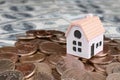 Mini house model on big coins stack on many dollar bills as background Royalty Free Stock Photo