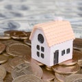 Mini house model on big coins stack on many dollar bills as background Royalty Free Stock Photo