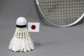 Mini Japan flag stick on the white shuttlecock on the grey background and out focus badminton racket