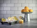 Mini lemon cupcakes with white and yellow swirled frosting sitting in a metal tray garnished with artificial lemon slices and a Royalty Free Stock Photo