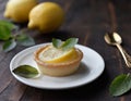 Mini lemon tart, decorated with a slice of lemon, on a dark wooden table