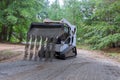 The Bobcat tractor moves and unloads gravel on the old road reconstruction site Royalty Free Stock Photo