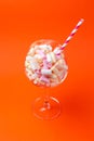 Mini marshmallows in a glass on a bright orange background. Multi-colored marshmallows in a glass Royalty Free Stock Photo