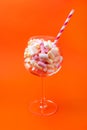 Mini marshmallows in a glass on a bright orange background. Multi-colored marshmallows in a glass Royalty Free Stock Photo