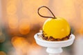 Mini mousse pastry dessert with yellow glazed on garland lamps bokeh background. Modern european cake. French cuisine