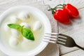 Mini mozzarella cheese balls with basil in bowl and two red cherry tomatoes on a  white rustic wooden table. Healhy mediterranean Royalty Free Stock Photo